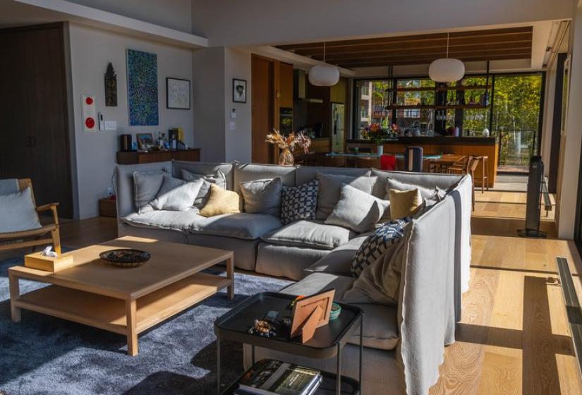 Luxurious open-concept living area in Chalet Lotus Niseko featuring comfortable gray sofas, wooden coffee tables, natural light streaming through large windows, and seamless flow to kitchen and dining spaces, perfect for social gatherings after skiing.
