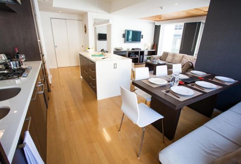 Alpen Ridge Niseko 2 bedroom apartment featuring spacious open-plan kitchen and dining area with wooden breakfast bar white dining chairs polished hardwood floors stainless steel appliances and contemporary mountain accommodation design