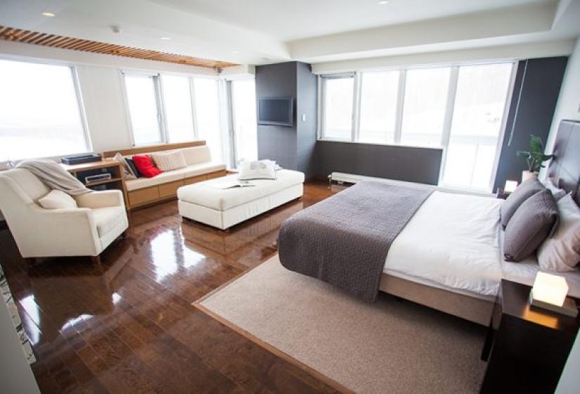 Alpen Ridge Niseko apartment featuring spacious open-plan design with king bed sofa seating area wooden floors large windows and modern furnishings