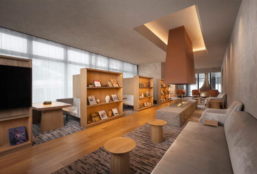 A lounge area with book cases and small round tables