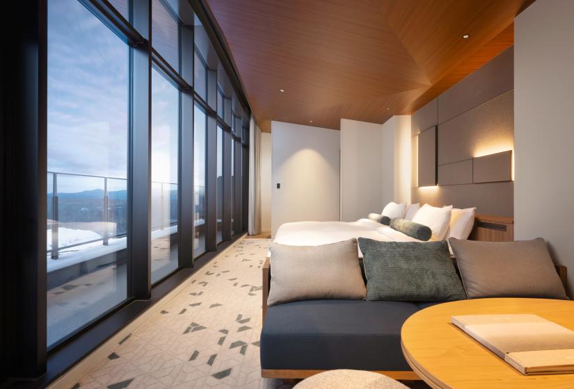 A room with large windows and lounge suite in the foreground