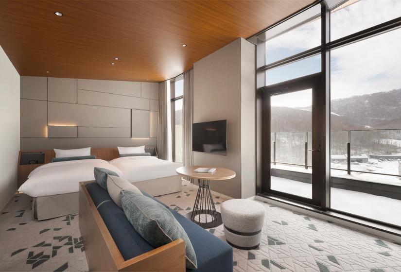 Two made up single beds with lounge suite in front