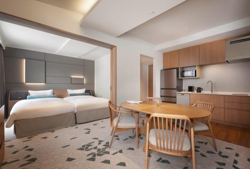 A round dining table beside kitchenette with bed behind