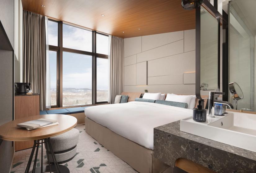 A made up double bed with sink in foreground