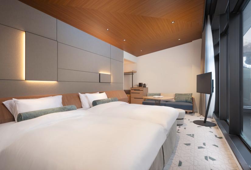 Two made up beds with TV behind to the right
