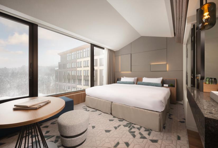 A made up double bed with windows to the left